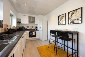 a kitchen with a counter and two bar stools at Spacious Apartment near MCR Airport in Wythenshawe +33 photos