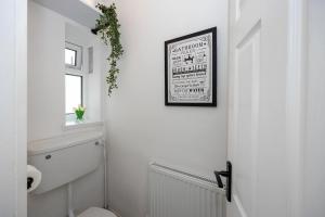 a bathroom with a toilet and a picture on the wall at Spacious Apartment near MCR Airport in Wythenshawe