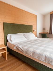 a bedroom with a large bed with a green headboard at Dolomiti Hotel Cozzio in Madonna di Campiglio