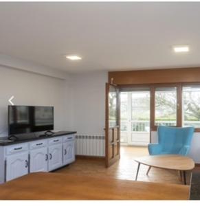 a living room with a tv and a blue chair at apartamento 1 matrimonial con terraza acristalada in Tapia de Casariego