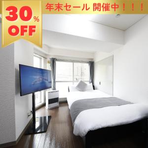 a bedroom with two beds and a flat screen tv at クレストコート北大前 in Sapporo