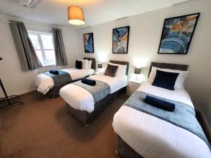 une chambre avec trois lits dans une pièce dans l'établissement Hythe House - Stylish Stay for Families & Groups by Catchpole Stays, à Colchester