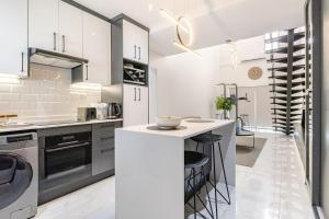 a kitchen with white cabinets and a counter with stools at The Icons Lounge - Exclusive Penthouse in Fourways with Pool Table in Fourways