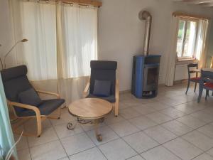 a living room with chairs and a table and a stove at Duplex l'Astrolabe in Les Geneveys-sur-Coffrane