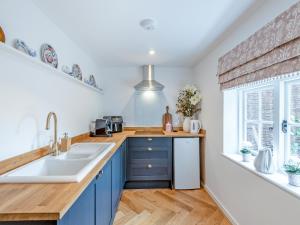 a kitchen with blue cabinets and a brick wall at The Studio in Wittersham +10 photos