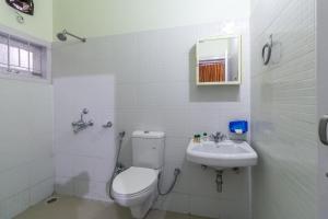 a white bathroom with a toilet and a sink at Tusti Homestay in Guwahati +18 photos