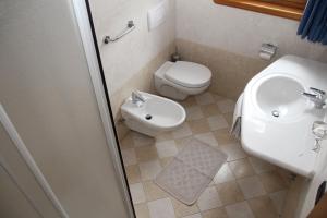 La petite salle de bains est pourvue de toilettes et d'un lavabo. dans l'établissement Albergo Caravasc, à Livigno
