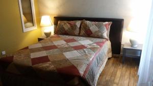 a bedroom with a bed with a quilt and two lamps at Le Rockin' Chair in Surzur