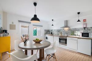 Una cocina con gabinetes blancos y una mesa y sillas. en Casa Amarela, en Tavira