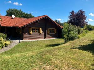 ein Blockhaus mit einem roten Dach und einem Hof in der Unterkunft Landhaus An der Schafgasse in Spittelstein