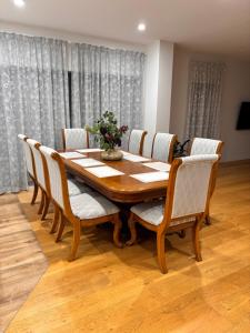 a dining room table with white chairs and a wooden table at Dream House 5 in Auckland
