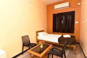 a small room with a bed and a table and chairs at Thilo Guest House Auroville in Auroville