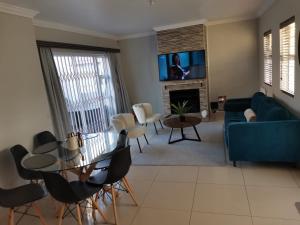 Una sala de estar con un sofá azul y una mesa. en Cosy 3 bedroom, en Cape Town 8 fotos más