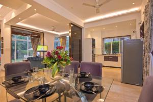 una sala da pranzo con tavolo in vetro e sedie viola di Golden Villa 4 Bhk With Private Swimming Pool Centrally Located a Lonavala