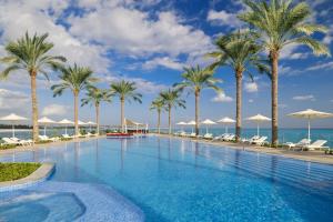 a swimming pool with palm trees and the ocean at Address Beach Resort Marassi in El Alamein