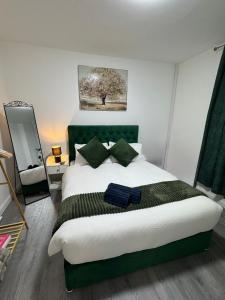 a bedroom with a large bed with a green headboard at City Escape Stylish 4 bedroom house in Nottingham in Nottingham