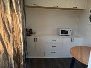 a kitchen with white cabinets and a microwave at Taree CBD Tiny backyard POD in Taree
