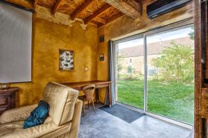 a living room with a couch and a large window at L'Apto - Gîtes à la ferme - Jardin avec plancha in Chicheboville