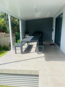 a patio with a table and a bench on it at Seaside Escape - 5 BR 2 Kitchens in Port Macquarie +36 photos