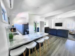 a kitchen and living room with a counter and stools at Seaside Escape - 5 BR 2 Kitchens in Port Macquarie