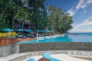 a resort swimming pool with chairs and umbrellas at Sepa Island Resort in Pulau Tondan Barat