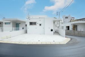 un edificio blanco al costado de una calle en Dual Life House Koza, en Okinawa City