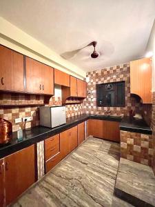 una cocina con armarios de madera y encimeras negras en Entire villa near Medanta Hospital, en Gurgaon