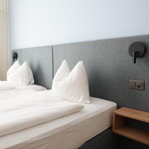 a bedroom with two beds with white pillows at Seminar-Hotel Rigi am See in Weggis