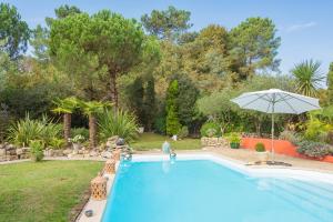 a swimming pool with an umbrella next to a yard at Sur la route des châteaux du Médoc in Blanquefort