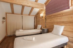 Dos camas en una habitación con paredes de madera. en Chalet du Verney - Pied du Prarion - Sauna, en Les Chavants