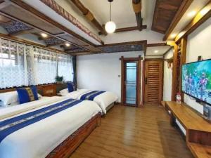Un dormitorio con dos camas y un televisor de pantalla plana. en Wuling Spring Inn, Yongding District, Zhangjiajie City, 