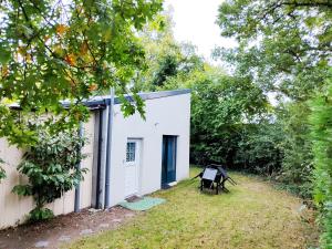ein weißes Gebäude mit einer blauen Tür neben einem Hof in der Unterkunft Studio Grimm - Tiny House in Le Cellier