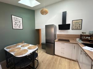 a kitchen with a counter and a table and a refrigerator at La Maison D'isaure 6 personnes Parthenay centre in Parthenay +23 photos