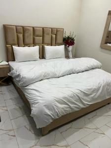 a large bed with white sheets and a vase of flowers at Kings Hotel in Dargai