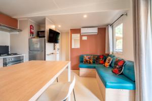 een woonkamer met een blauwe bank en een keuken bij Mobilhome au Camping La Yole in Vendres-Plage