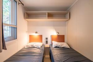 twee bedden in een kleine kamer met een raam bij Mobilhome au Camping La Yole in Vendres-Plage