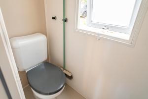 een kleine badkamer met een toilet en een raam bij Mobilhome au Camping La Yole in Vendres-Plage +18 foto's