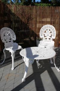 2 sedie bianche e un tavolo su un patio di The Nestle - A Romantic Rural Retreat a Ilminster