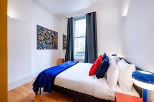 1 dormitorio con 1 cama con almohadas rojas y azules en Welcome London Covent Garden Piazza, en Londres