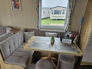 a living room with a table and a couch at Thurston Manor Caravan Park, Pony Meadow in Innerwick