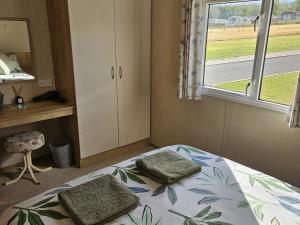 a bedroom with a bed and a window at Thurston Manor Caravan Park, Pony Meadow in Innerwick
