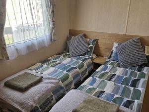 two beds sitting next to each other in a room at Thurston Manor Caravan Park, Pony Meadow in Innerwick