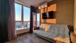 a living room with a couch and a tv on a wall at Lebedinny Flat in Kyiv
