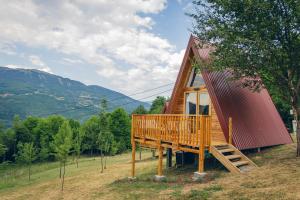 a cabin with a large deck in a field at Camp Nomad Sutjeska in Tjentište