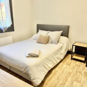 a bed with white sheets and pillows in a room at Appartement proche de l'hôpital in Tulle