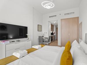 a bedroom with a large white bed with a flat screen tv at The Comfort Cove Studio in Azizi Riviera 44 in Dubai