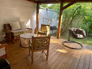 Una habitación con un porche con una mesa y un columpio. en Maison Zen avec jacuzzi privatif, en Étang-Salé