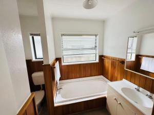 a bathroom with a bath tub and a sink at Cosy 3 Bedrooms House Beside City Centre in Hamilton +13 photos
