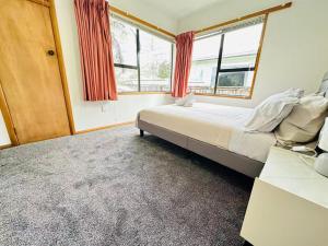 a bedroom with a bed and two windows at Cosy 3 Bedrooms House Beside City Centre in Hamilton