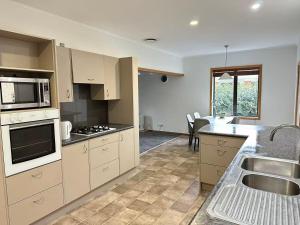 a kitchen with a sink and a stove top oven at Cosy 3 Bedrooms House Beside City Centre in Hamilton